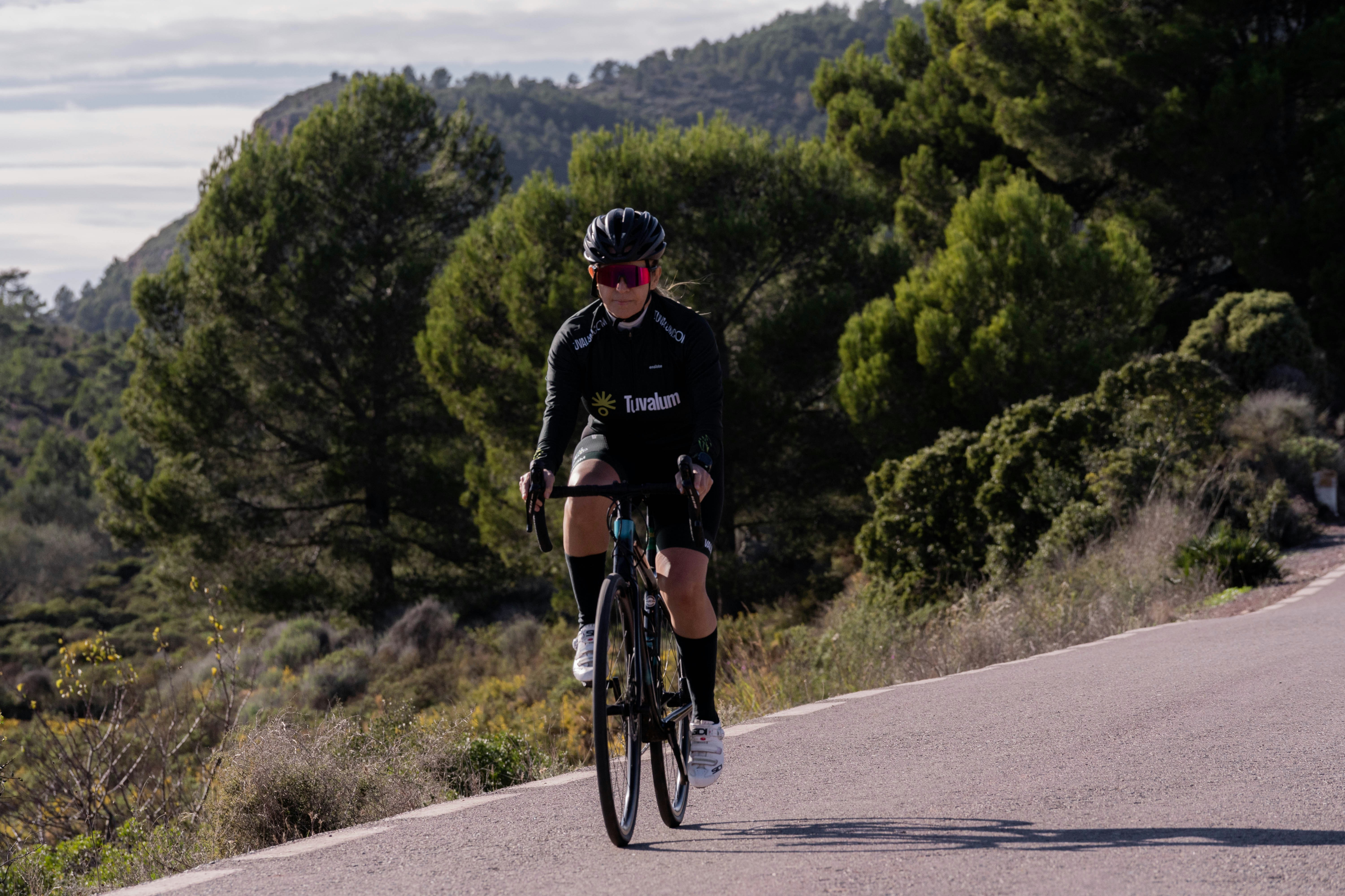 a man riding a bike down a road next to a forest