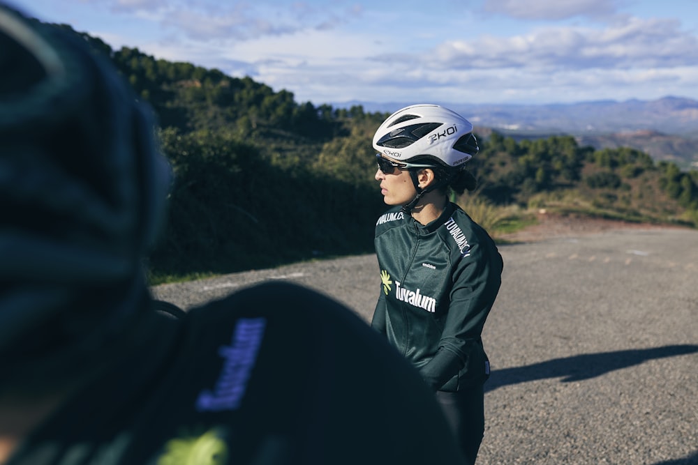 a person wearing a helmet standing on the side of a road