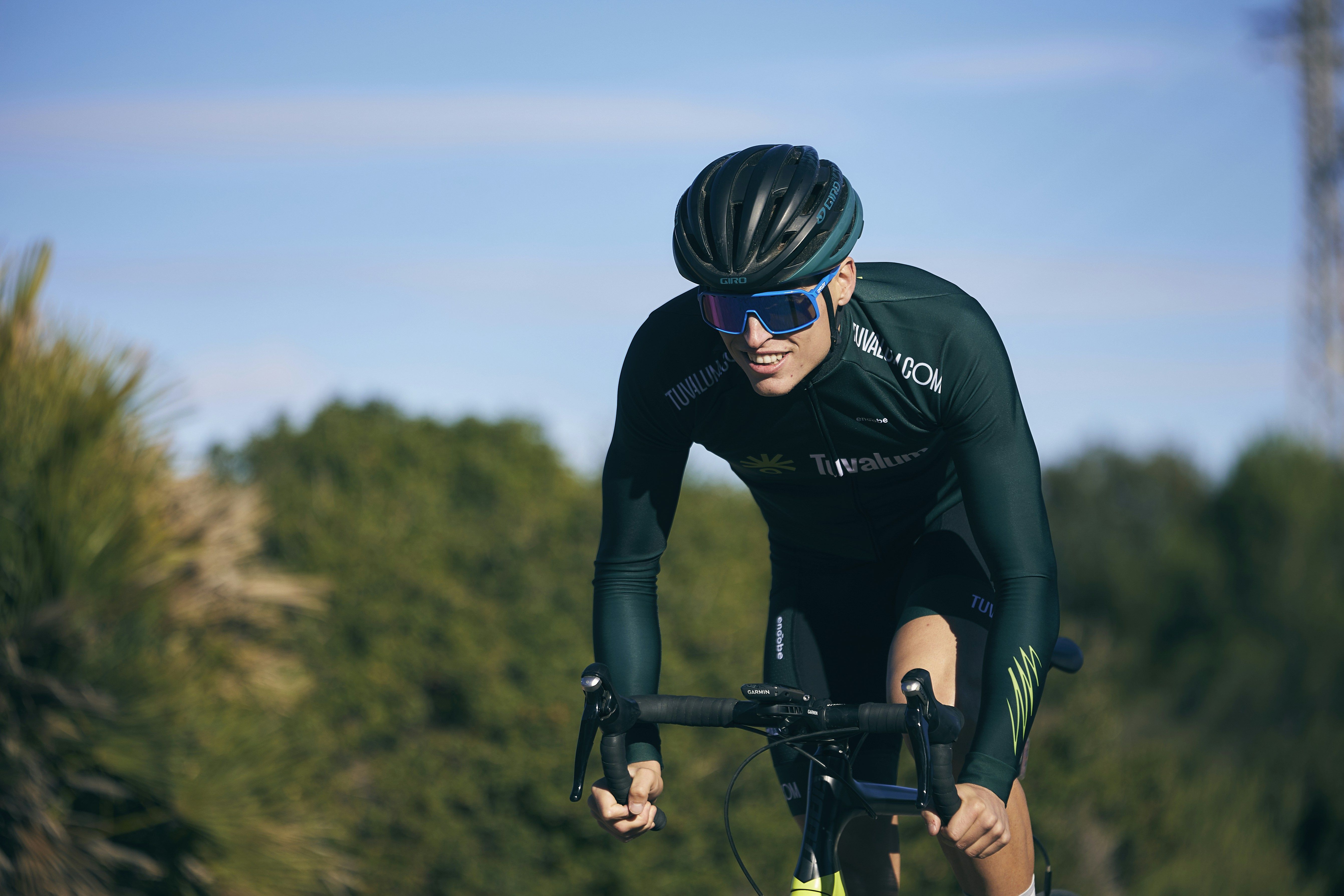 a man riding a bike down a road next to a forest