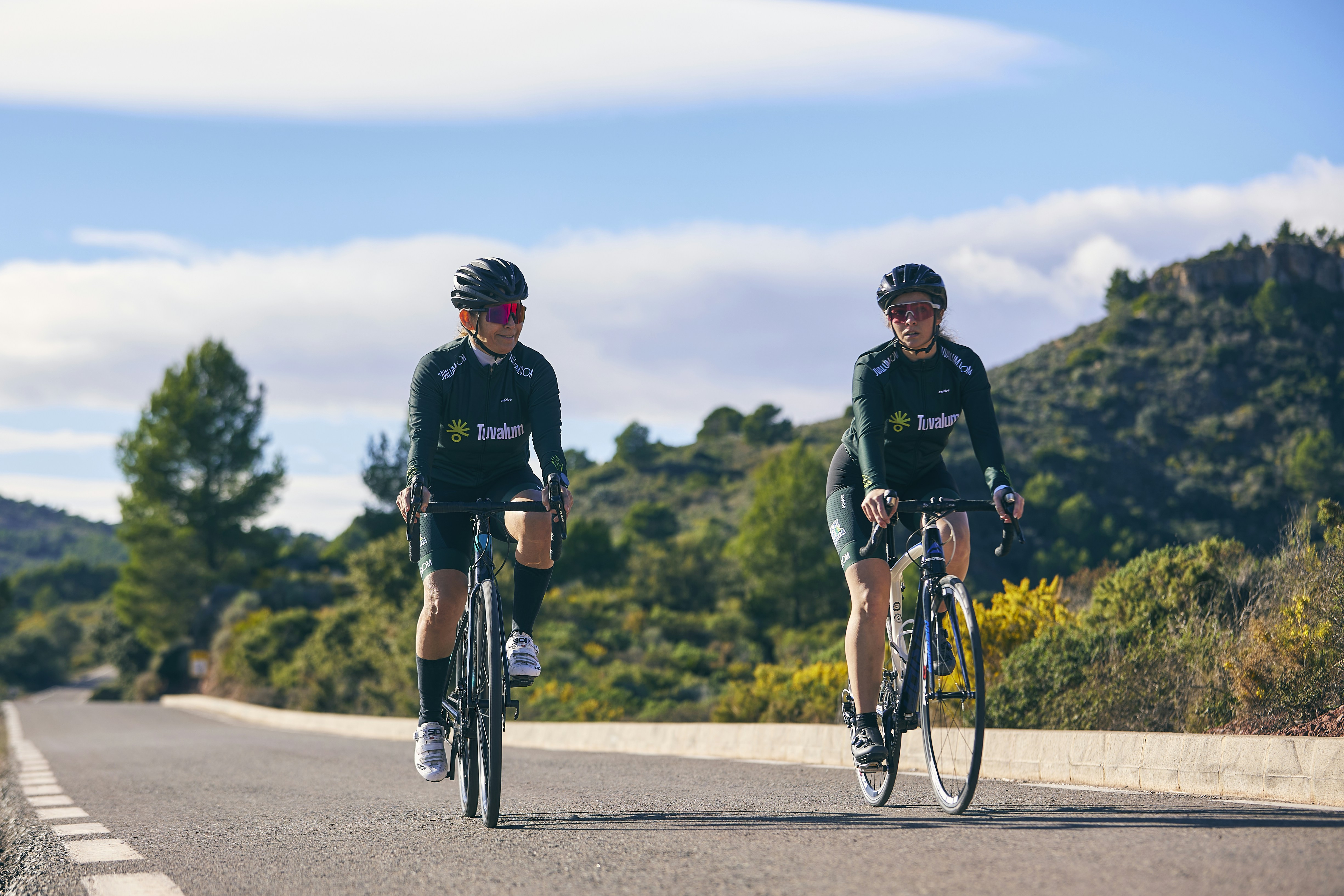 a couple of men riding bikes down a road