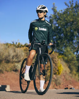 A cyclist lubricating the bike chain on a sunny day outdoors.
