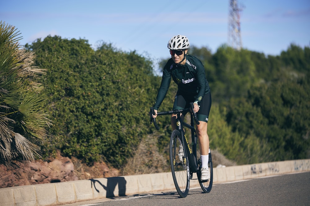 a man riding a bike down a street next to a forest