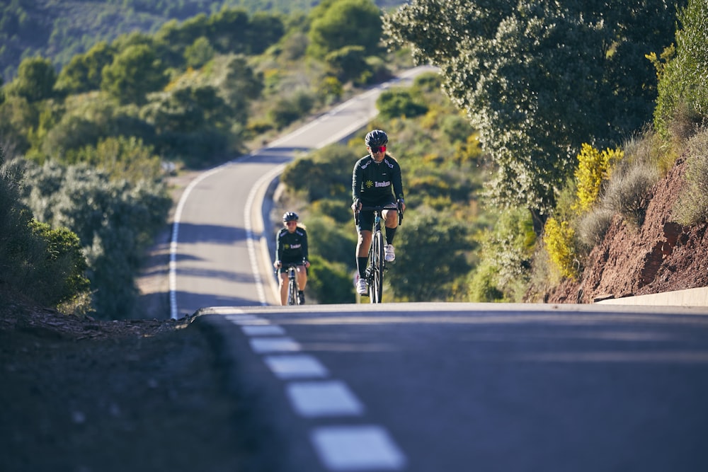 a couple of people riding bikes down a road