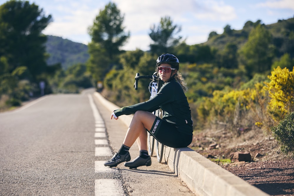 a woman sitting on a bench on the side of a road