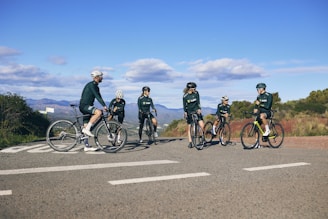 Group of riders pausing on a lush green valley overlook, sharing laughs and layered mountain views.