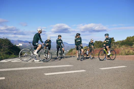 Group of cyclists resting beside a historic church in Acambay under a clear blue sky.