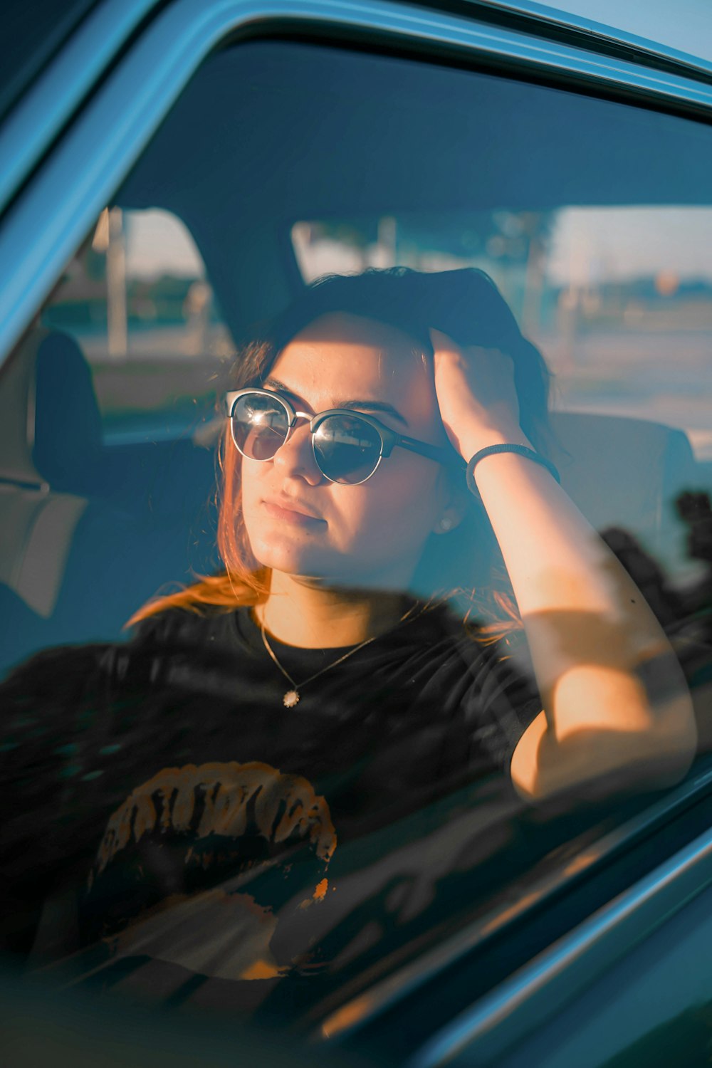 a woman sitting in a car with her hand on her head