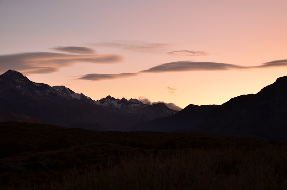 the sun is setting over a mountain range