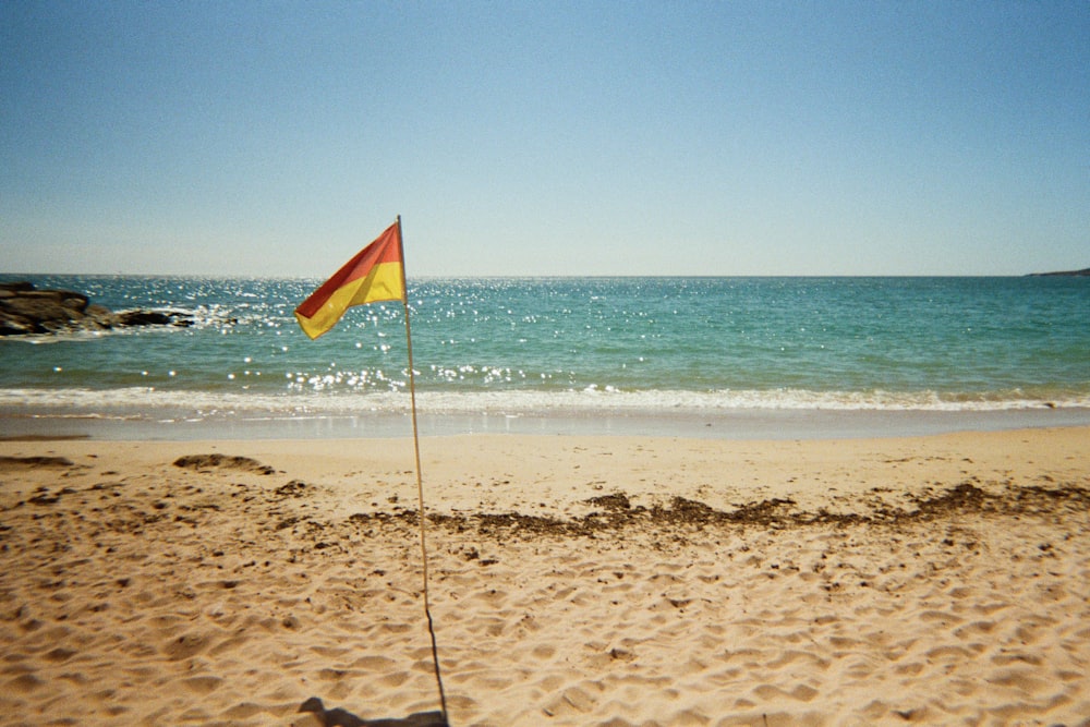 a flag sticking out of the sand on a beach