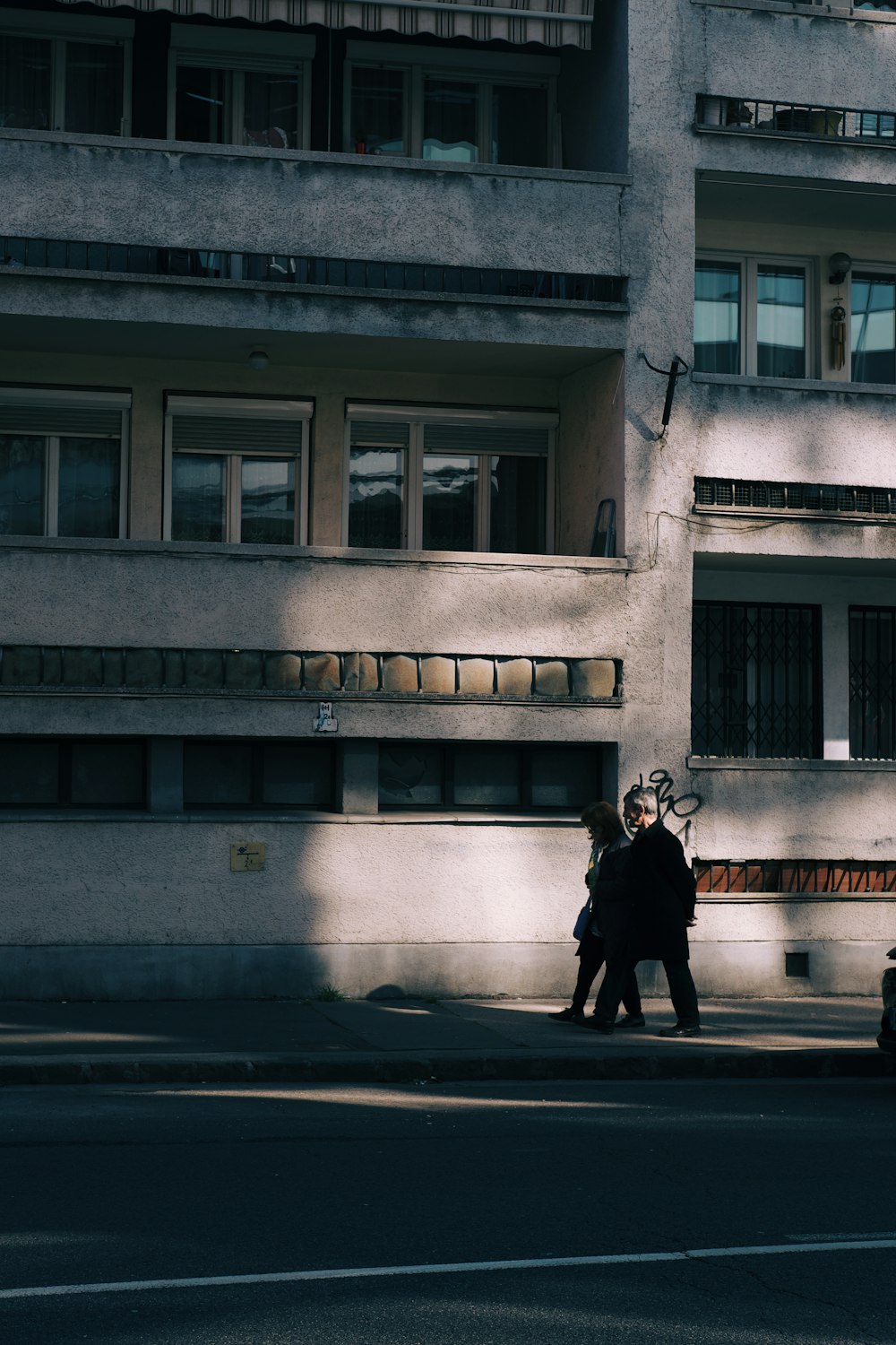 a couple of people walking down a street next to a tall building