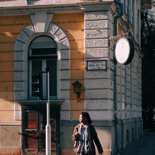 a woman walking across a cross walk in front of a building