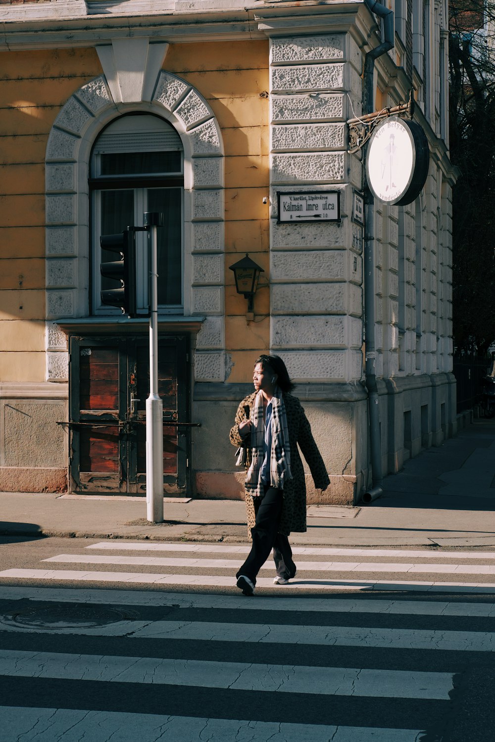 a woman walking across a cross walk in front of a building