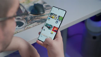 Close-up of a shopper happily browsing colorful products on a smartphone, with a cozy home background.