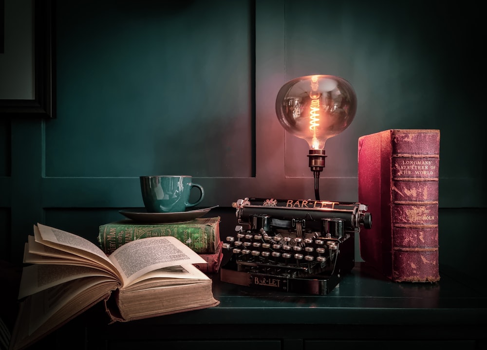 uma mesa com uma lâmpada, um livro e uma máquina de escrever sobre ela