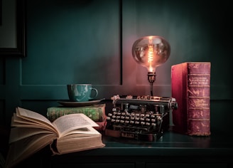 a table with a lamp, a book, and a typewriter on it