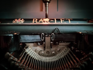 A vintage typewriter viewed from the front, focusing on the intricate mechanics and the type bars. The word 'BAR-LET' is prominently displayed above, adding a nostalgic feel.