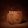 A leather handbag with intricate butterfly and floral designs, predominantly in shades of red, green, and purple. The background is a rich brown, giving a natural, earthy feel to the piece.