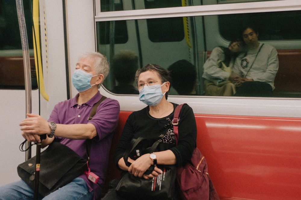 a man and a woman sitting on a bus wearing masks