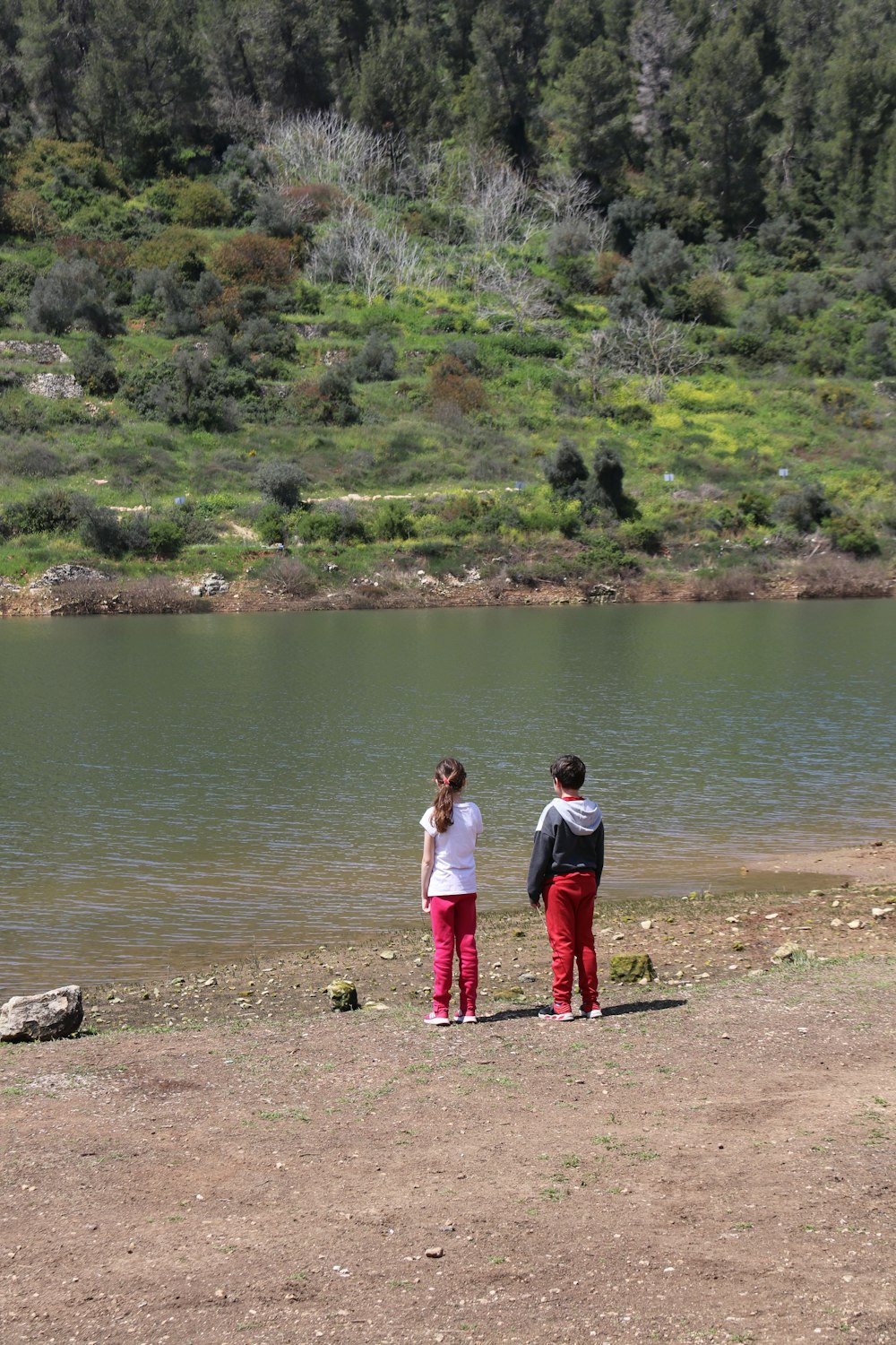 a couple of people standing next to a body of water