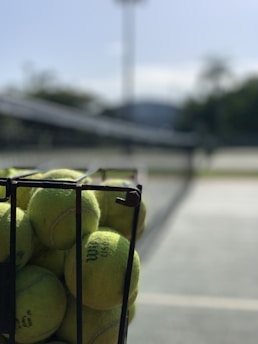 a basket full of tennis balls on a tennis court