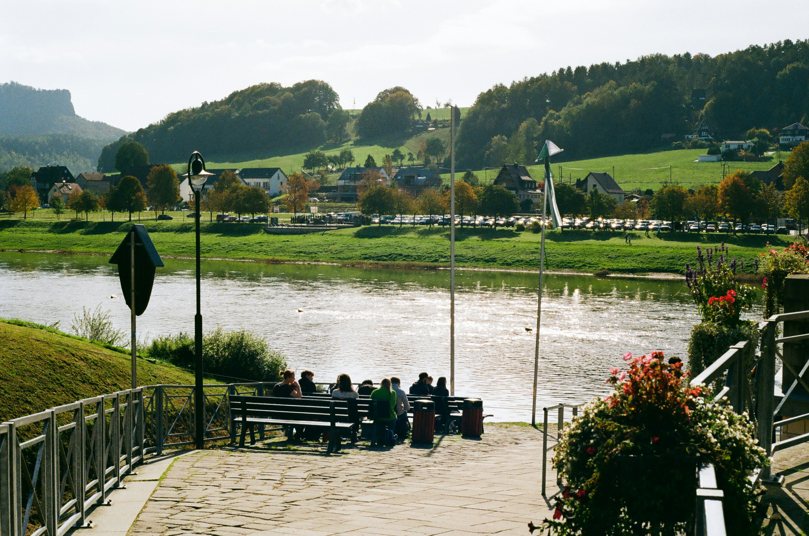 a group of people sitting on a bench next to a river