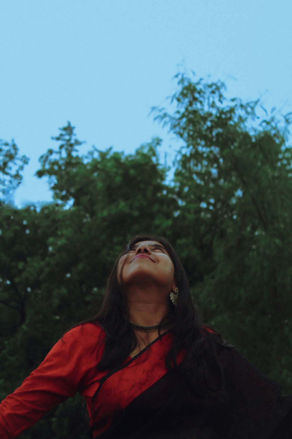 a woman in a red shirt is flying a kite