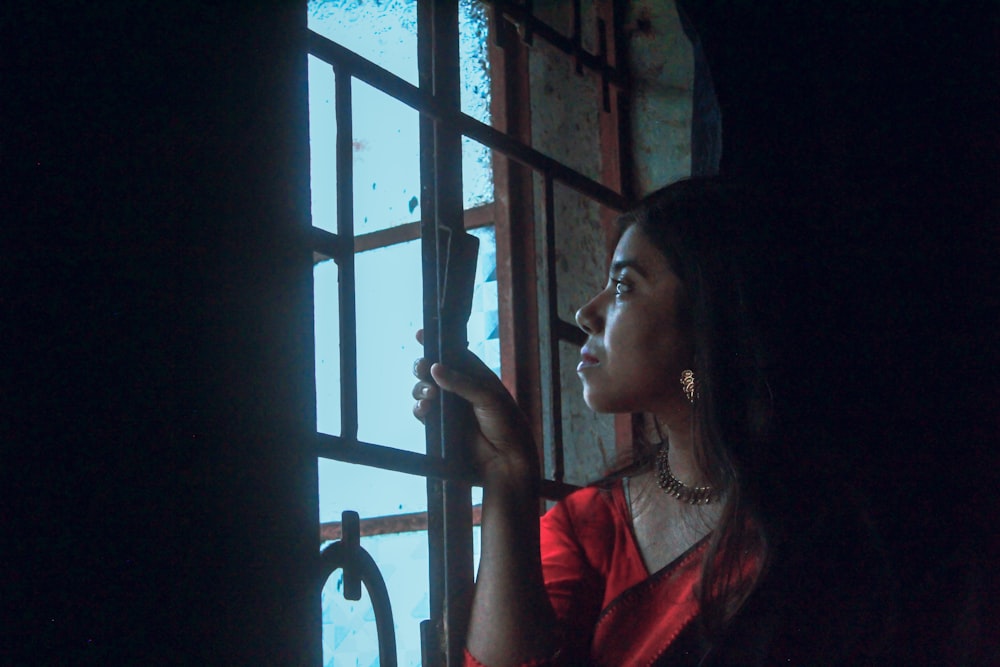 a woman in a red dress looking out a window