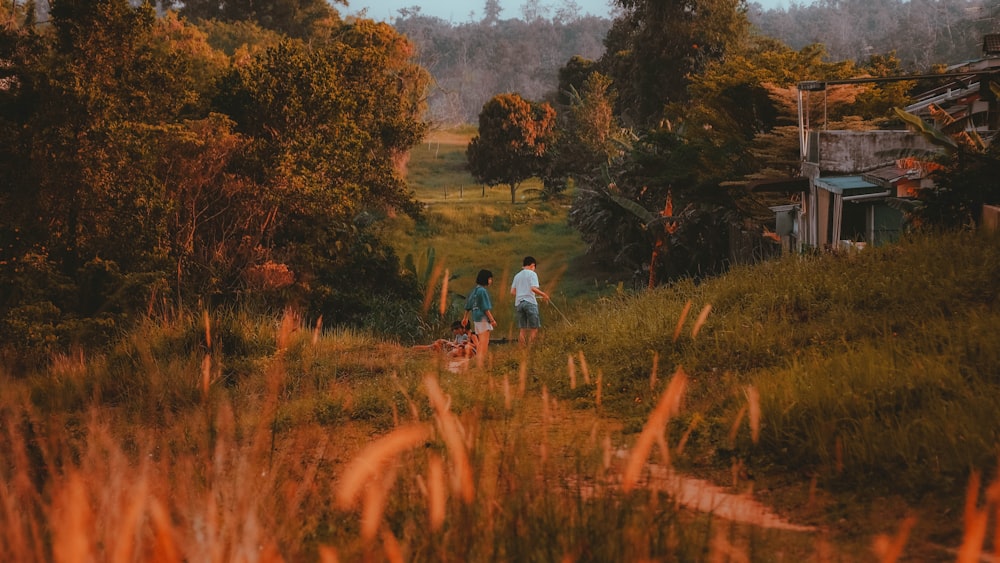 a couple of people walking a dog down a dirt road