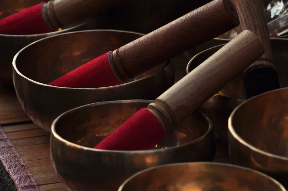 a close up of many metal bowls with wooden handles