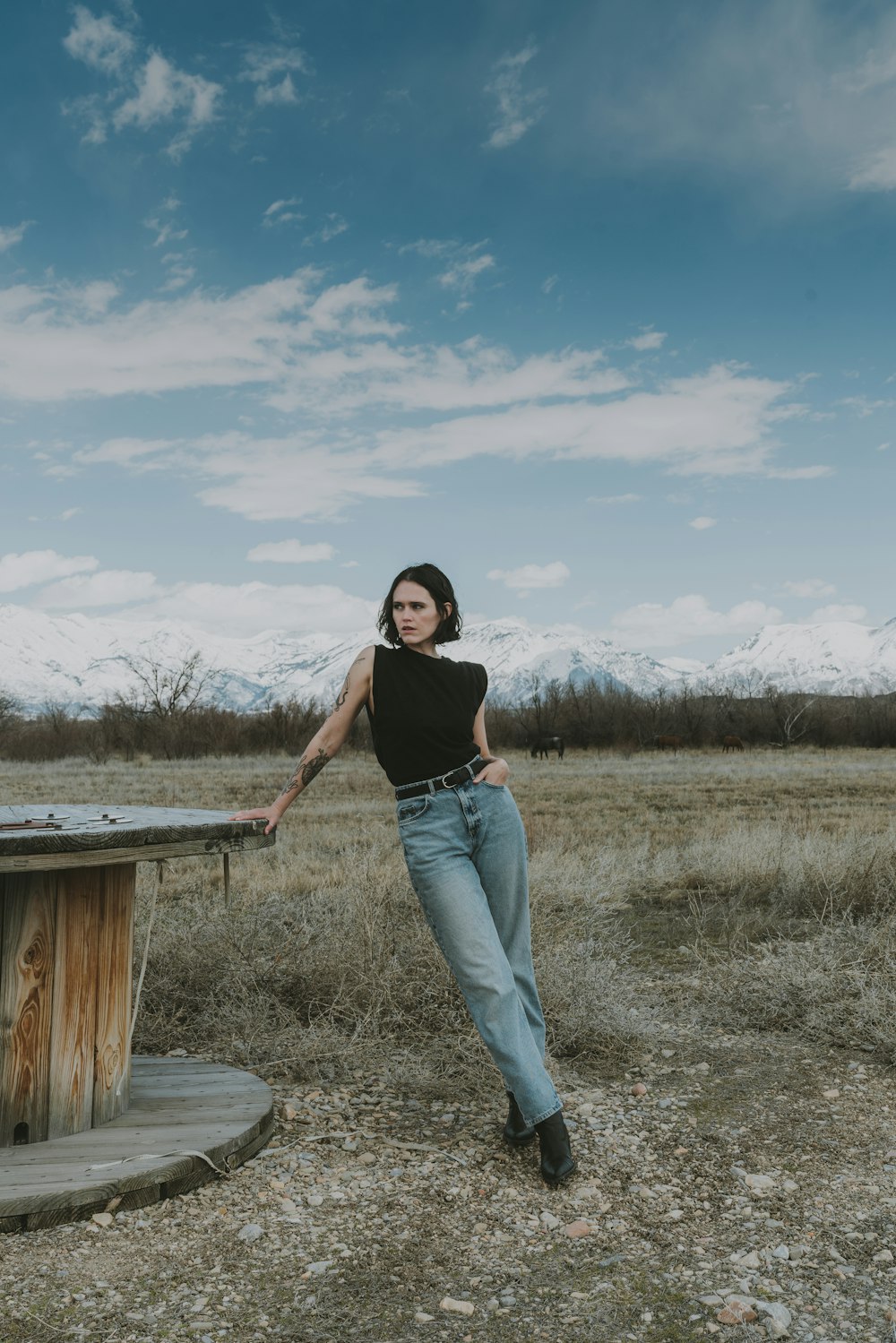 a woman standing next to a wooden table in a field