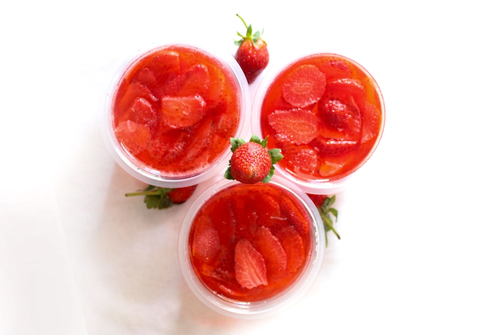 three small cups filled with strawberries on top of a table