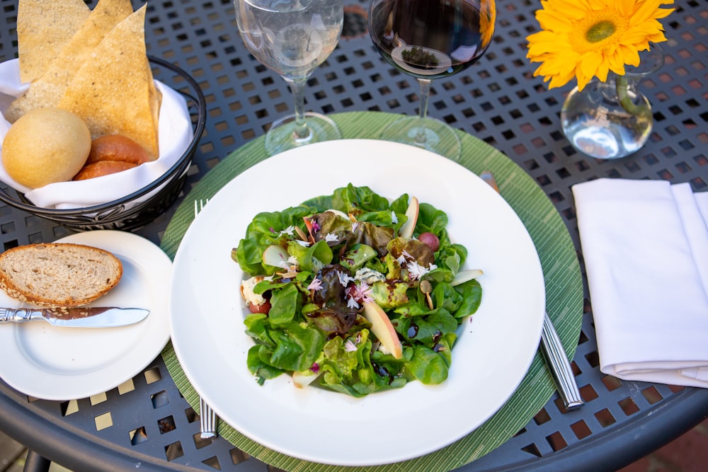 a plate of salad and a glass of wine on a table