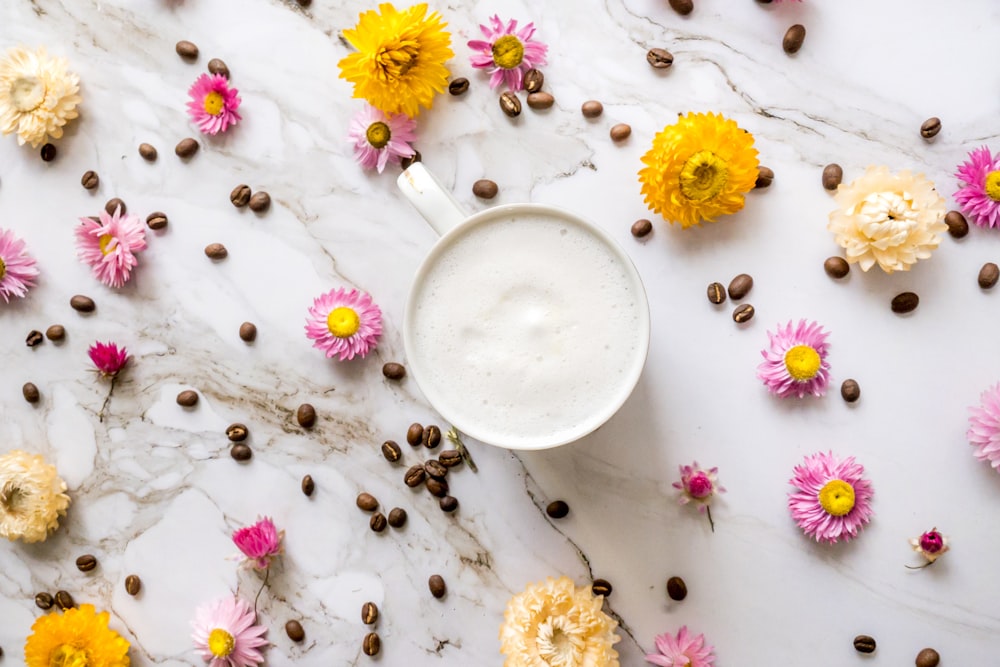 una taza de café rodeada de granos de café y flores