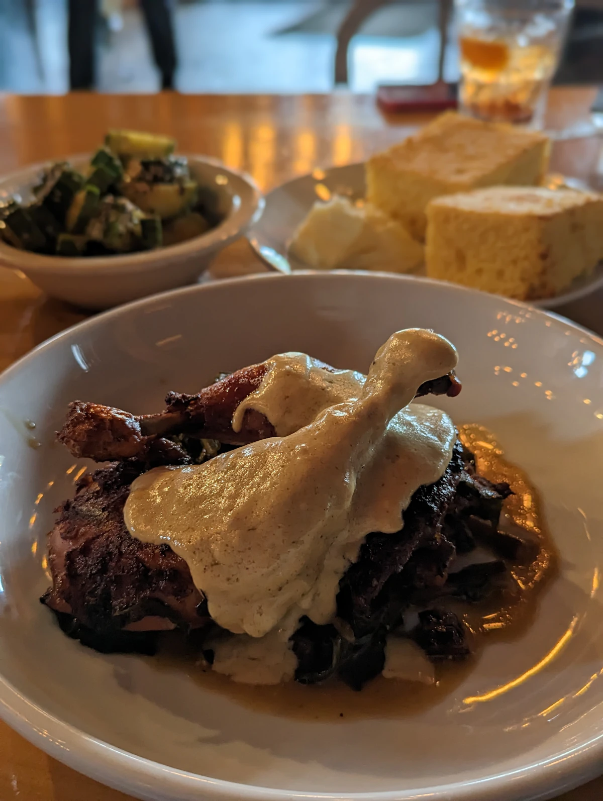 Smothered chicken under gravy over greens with cornbread and okra alongside