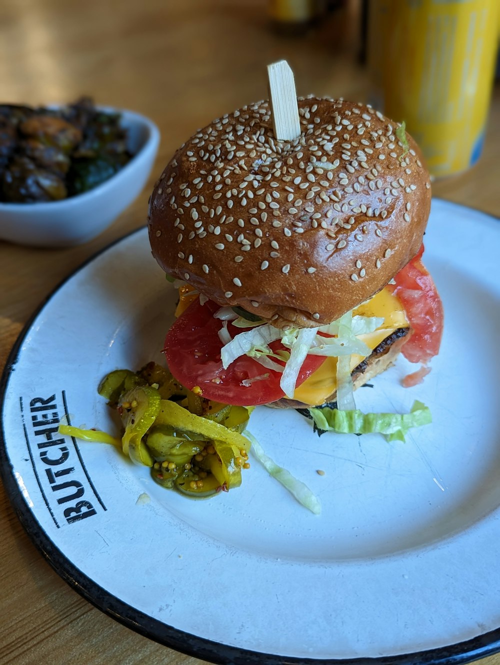 a hamburger on a plate with a side of pickles