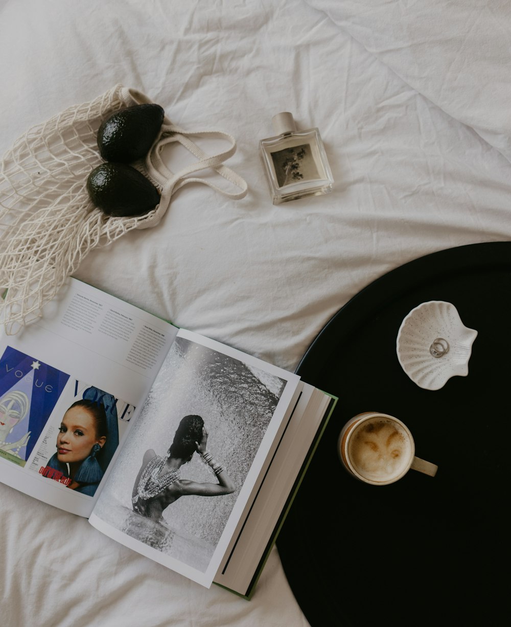 an open book sitting on top of a bed next to a cup of coffee