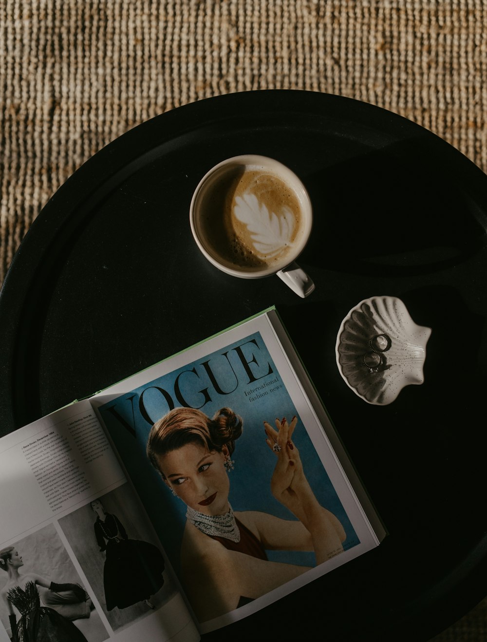 a magazine sitting on top of a table next to a cup of coffee
