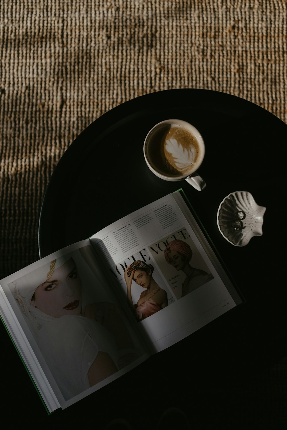 an open magazine sitting on top of a table next to a cup of coffee