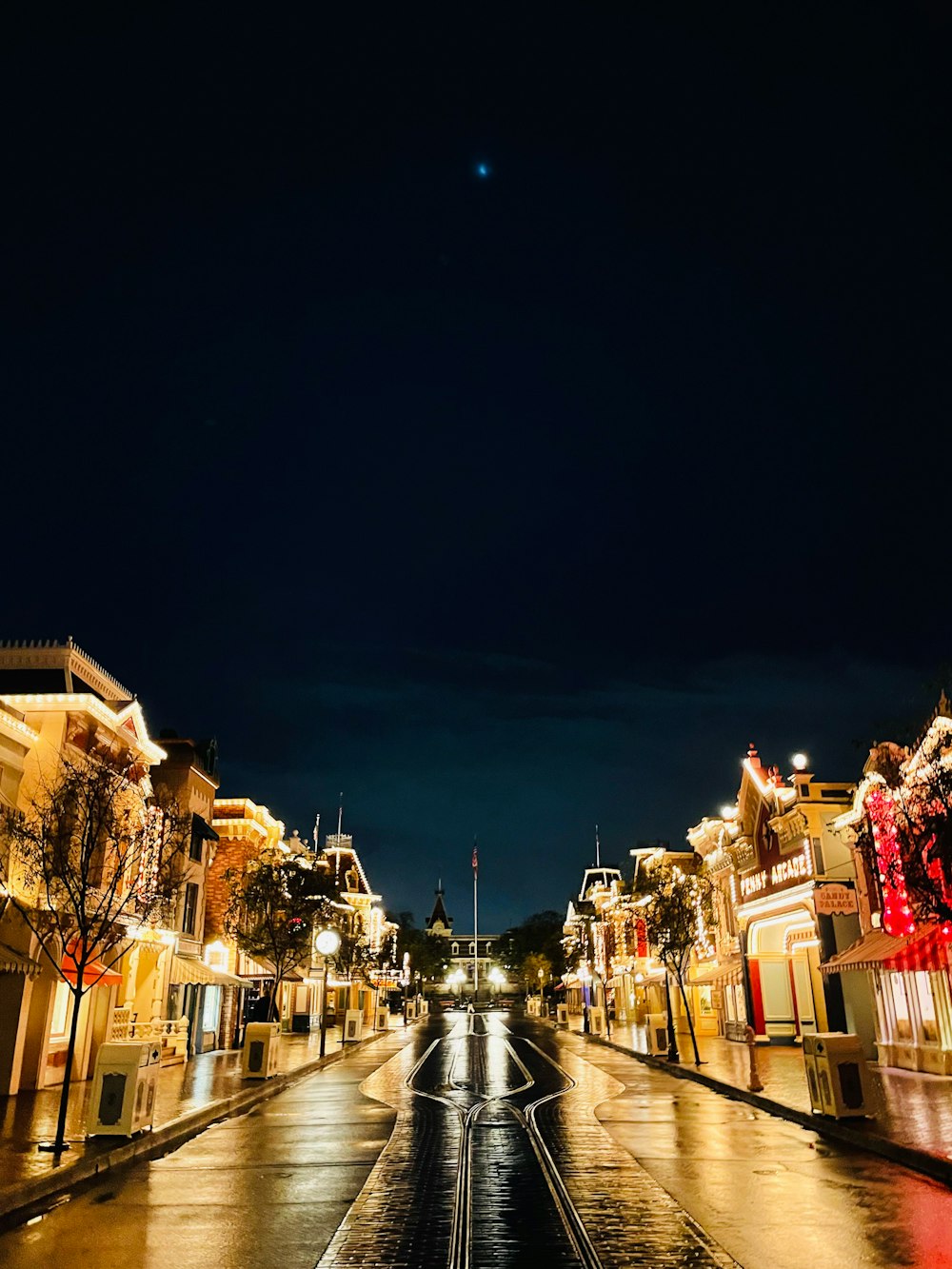 a wet street at night with lights on buildings