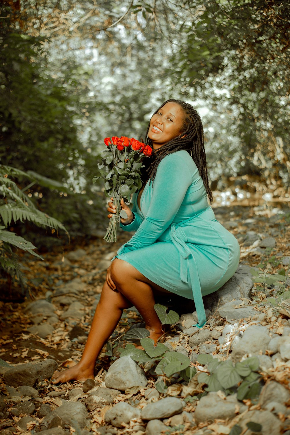 a woman sitting on a rock holding a bouquet of flowers