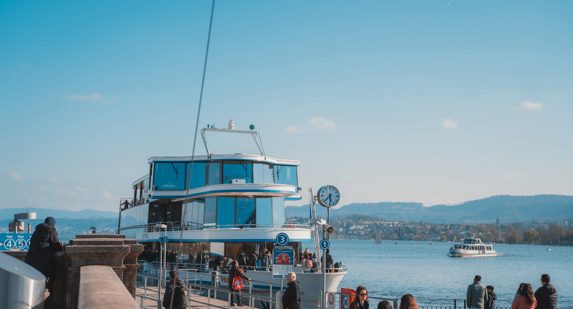 An aqua current boat docked at a charming canal-side village, reflecting the harmony of modern design with timeless waterside scenery.