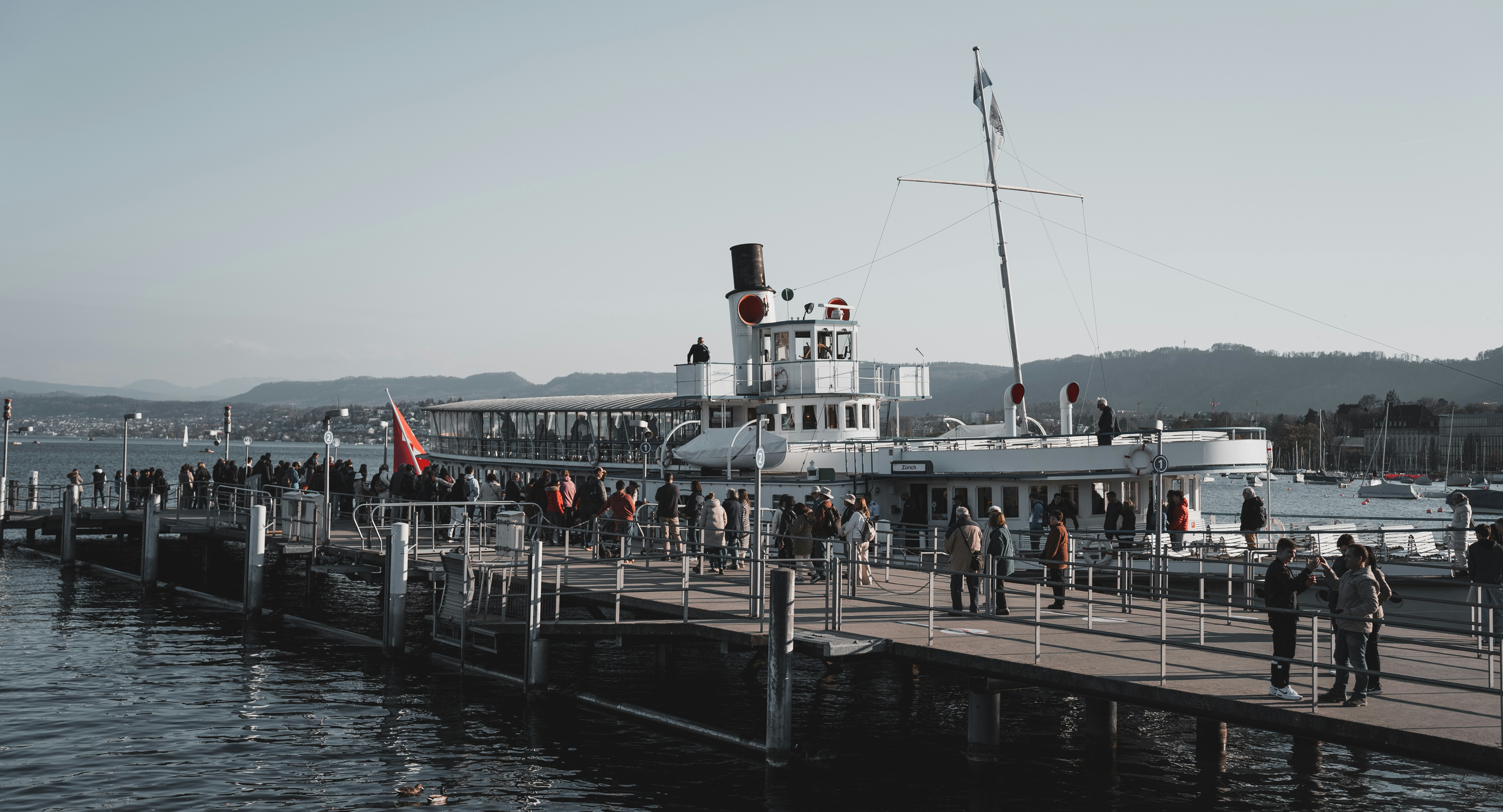 a group of people standing on a pier next to a boat