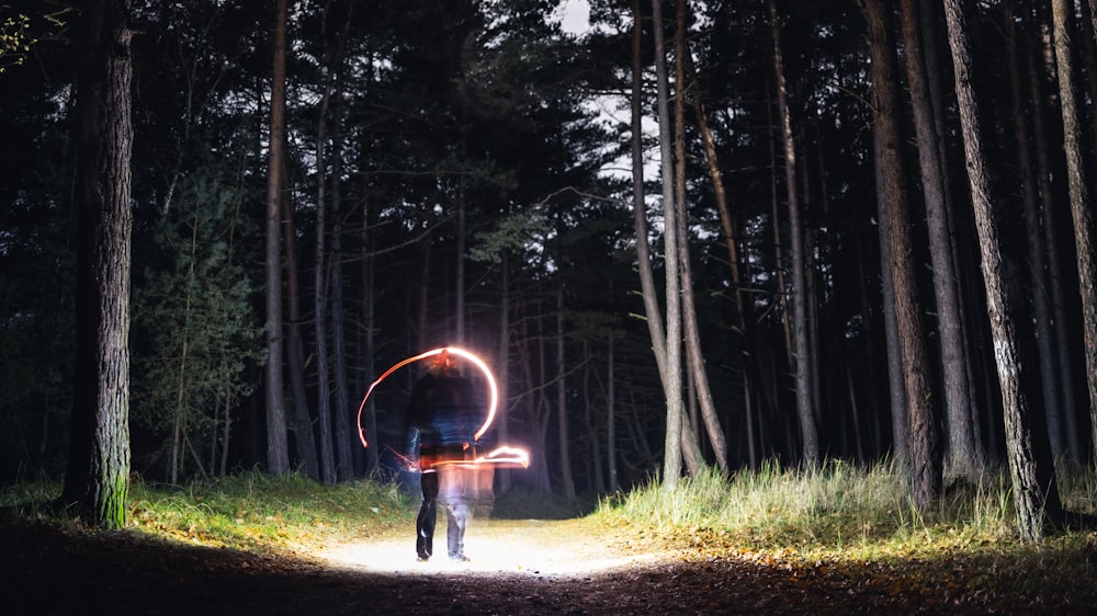 a man holding a light up in the middle of a forest
