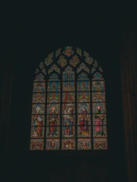 A detailed photograph showing artisans restoring the intricate stained glass windows of Sint-Catharinakerk.