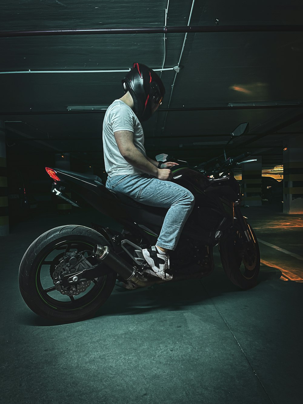 a man sitting on a motorcycle in a parking garage