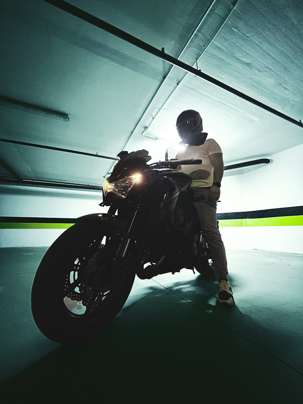 a person sitting on a motorcycle in a parking garage