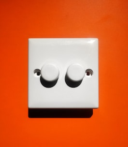 A sleek, modern alarm control panel mounted on a navy blue wall with orange accents.