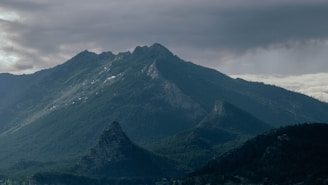 A mountain range with clouds rolling above, symbolizing the untamed beauty of Himalayan ecosystems.