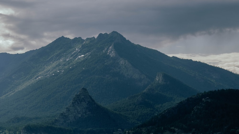 a mountain range with trees and clouds in the background