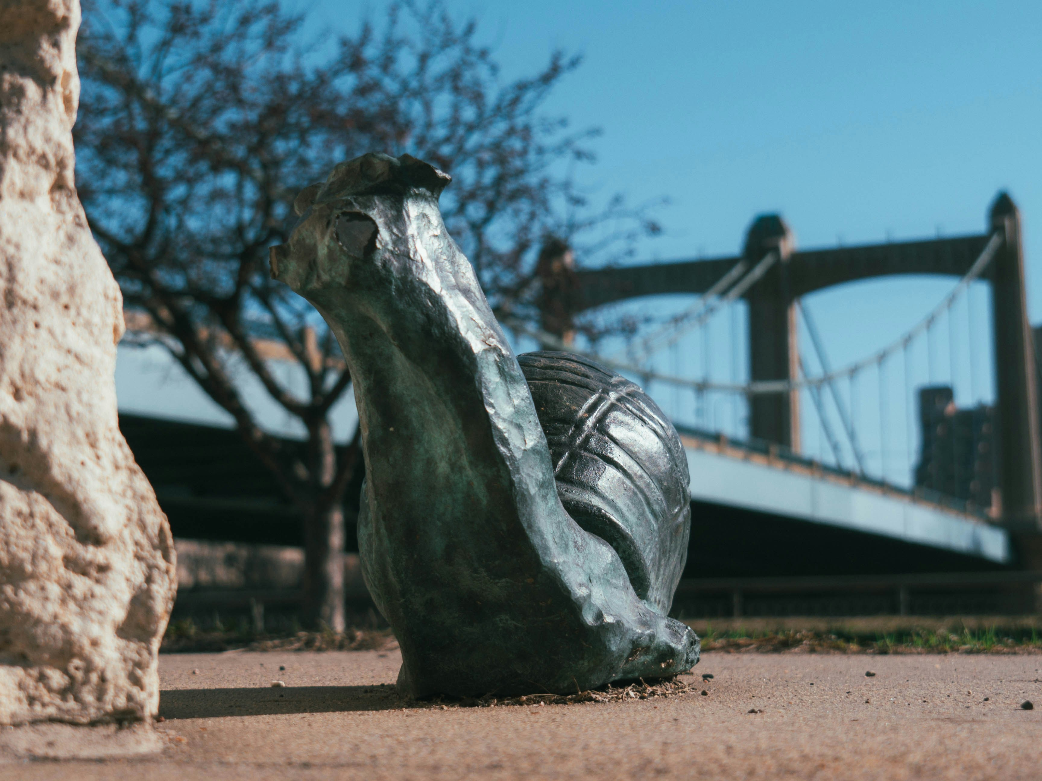 una estatua de un zapato en el suelo frente a un puente